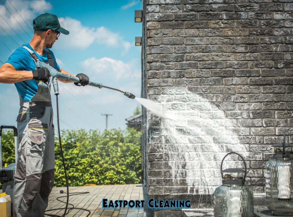 Professional pressure washing technician cleaning exterior brick building wall in Bradenton FL by Eastport Cleaning
